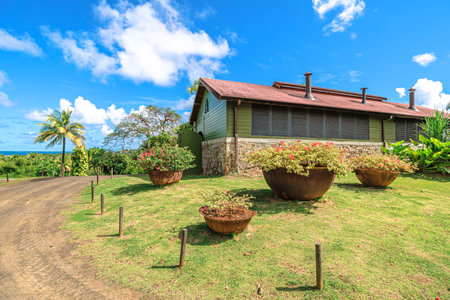 Martinique, French Antilles - Dec 26, 2025: 1710 Rhum Agricole distillery building with a porch covered in tropical vegetation, white shutters, and a green wooden colonial house facadeのeditorial素材