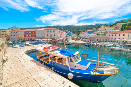 Blue fishing boat docked in Mali Losinj Kaciol harbor capturing the charming waterfront, traditional architecture, and clear Adriatic Sea waters of Losinj Island in Croatia