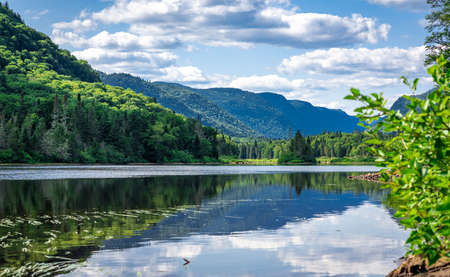 Awesome view of a lake and some verdant hills in Jacques Cartier National Park, Quebec province, Canada. Everything is green and mindblowing over here during summerの写真素材