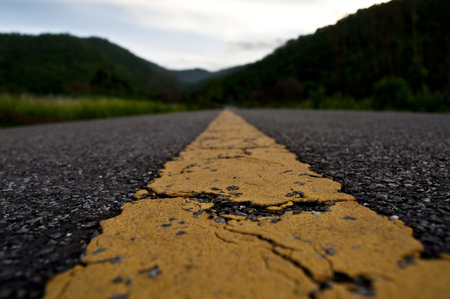 French road with a yellow central line, with blurred hills in the backgroundの写真素材