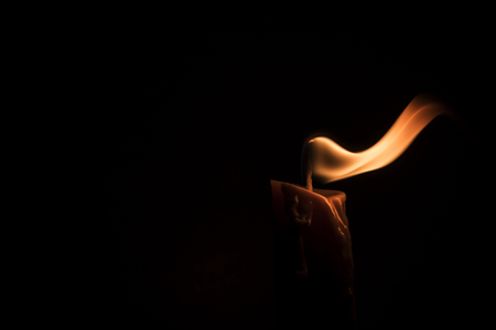 Close-up of a burning candle in a low-key imageの写真素材