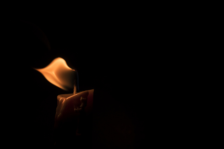 Close-up of a burning candle in a low-key imageの写真素材