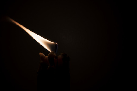 Close-up of a burning candle in a low-key imageの写真素材