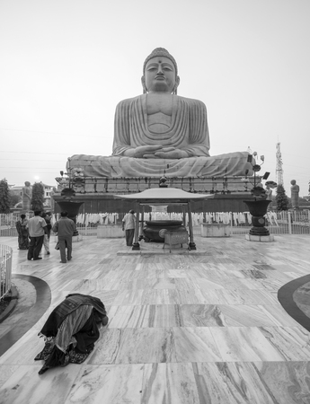 Woman prays on the floor in front of the Great Buddha Statue in Boh Gaya, Indiaのeditorial素材