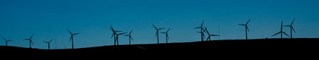 Silhouettes of wind turbines on a hill in Franceの写真素材