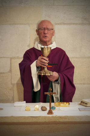 A Senior French Catholic priest is giving mass during a baptism in Aquitaine.のeditorial素材