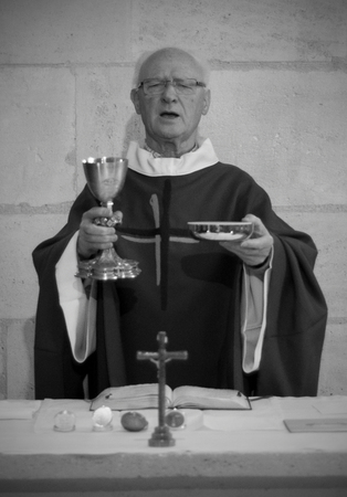 A Senior French Catholic priest is giving mass during a baptism in Aquitaine.のeditorial素材