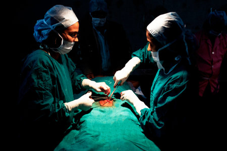 Surgeons and nurses conduct a tubal ligation on a young woman in Bihar, India.
