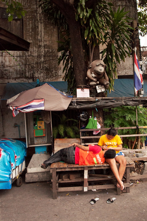 A motorbike-taxi driver gets his ears cleaned by a female friend in a street of Bangkok, Thailand.のeditorial素材