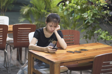 Vietnamese woman is browsing on her mobile on a restaurant terrace in Ho Chi Minh City, Vietnam.のeditorial素材