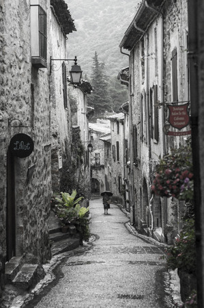 Woman walks by in a street of the medieval French village of Saint-Guilhem-le-DÃ©sert.のeditorial素材