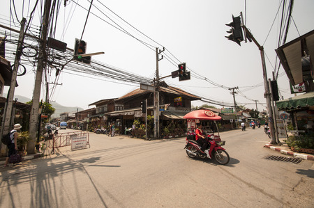 A mobile Walls ice  creams seller passes a quiet crossing on her motorbike in Pai, Thailand.のeditorial素材