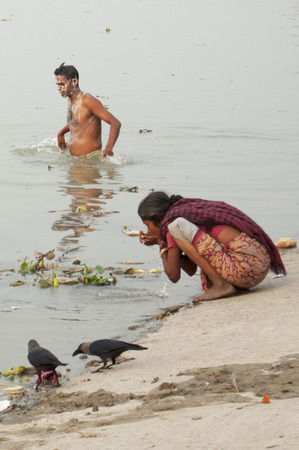 Indian woman drinks the Ganges' water as a man bathes in it in India.のeditorial素材