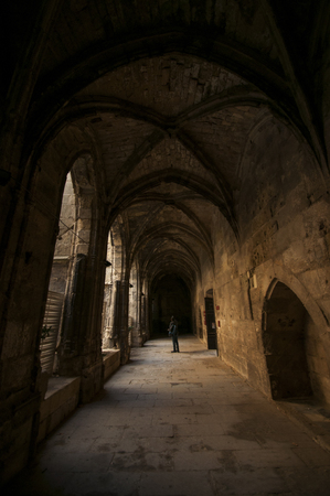 A single tourist looks around under the arches of the Palais des ArchevÃªques in Narbonne in the south of France.のeditorial素材