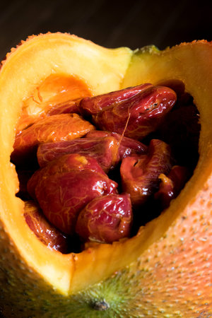 Half gac fruit on a wooden board.
