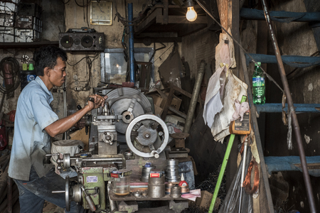 Indonesian worker operates his machine in an old workshop in Jakarta, Indonesia.のeditorial素材