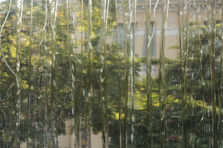Building seen through water flowing down a windowの写真素材