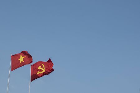 Vietnamese and communist flags in the wind on a blue skyの写真素材