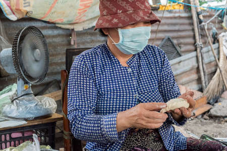 Vietnamese woman makes and sells snacks in a street of Ho Chi Minh Cityのeditorial素材