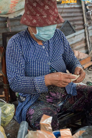 Vietnamese woman makes and sells snacks in a street of Ho Chi Minh Cityのeditorial素材