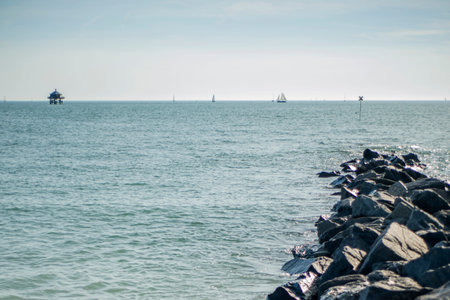 Rock jetty into the Atlantic Ocean, with boats on the horizon.