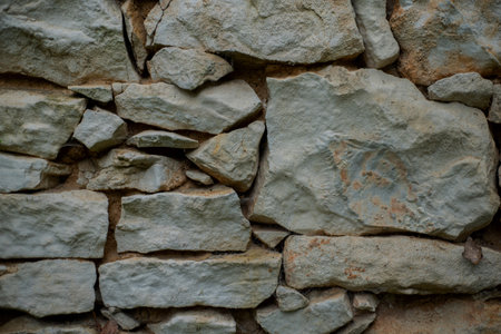 Background close up of a weathered traditional French house dry stone wall.