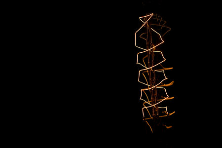 Turned on Edison bulb isolated against a black background.