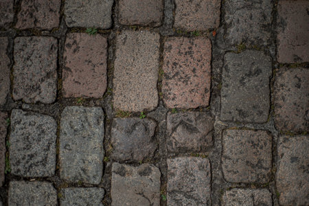 Closeup top view of cobblestones of different colors and textures from a medieval street in the...