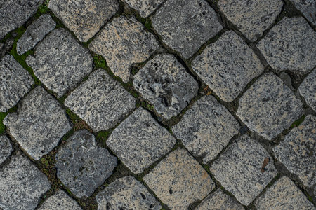 Closeup top view of cobblestones of different colors and textures from a medieval street in the...