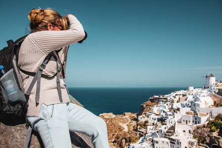 Woman with backpack photographing the island of Santorini.のeditorial素材