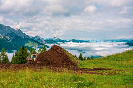 Excavator in the mountains. In the background the Dolomites, Italy.の写真素材