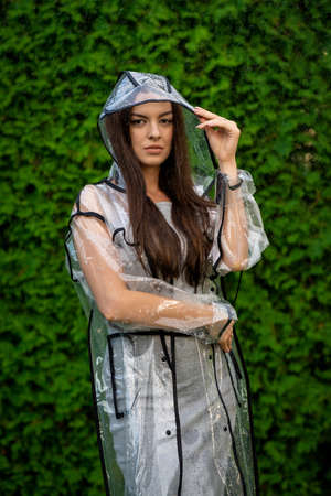 Young beautiful woman in hooded raincoat on rainy dayの写真素材
