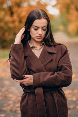 Young beautiful woman in brown coat in the park in autumnの写真素材