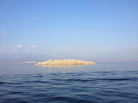 A blue sky and water with a little island in the middleの素材