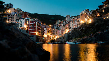 one of the five lands cities riomaggiore photographed from a low angle on the water as a long exposure at nightの写真素材
