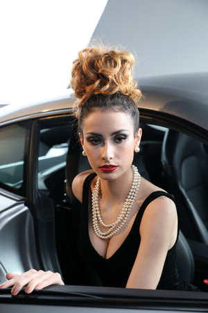 Nice, France - April 12, 2019: Cute Fashion Model With A Pearl Necklace Posing In A Sports Car,...