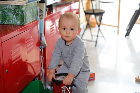 Cute Baby Boy Playing With Firefighter Ride-On Toy Car At Home, Close Up Portraitの写真素材
