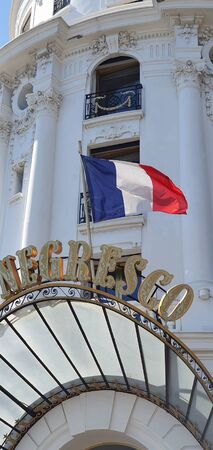 Nice, France - May 1, 2019: Famous Entrance of Hotel Negresco Facade And Sign On Promenade Des Anglais In Nice, Flag Of France Waving In The Wind, French Riviera, Provence-Alpes-Cote d Azur, France, Europeのeditorial素材