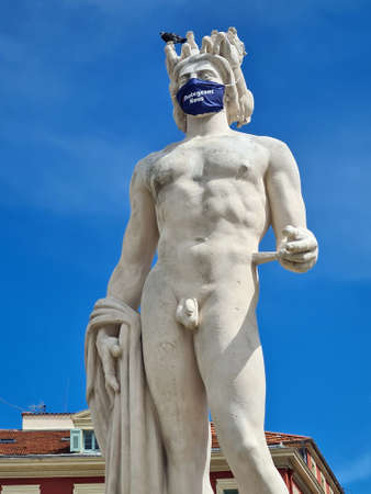 Nice, France - June 9, 2020: Close Up Of Apollo With Surgical Mask During Covid-19 Time, Fountain Of The Sun With A Marble Statue Of On Place Massena In Nice, French Riviera, France, Europeのeditorial素材