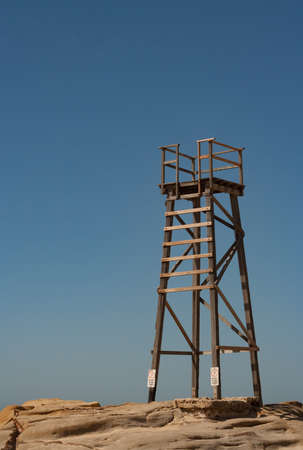Old wooden lifeguard tower on rocky outcropの写真素材