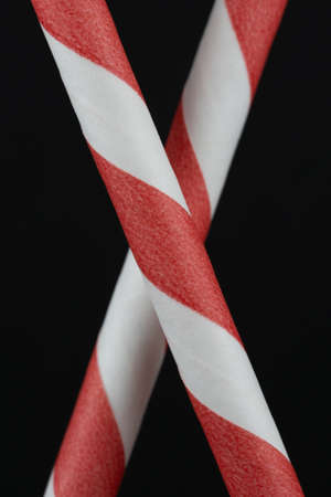 Macro portrait layout of two red and white paper straws on a black backgroundの写真素材