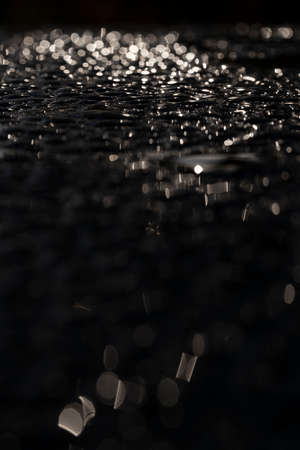 Macro image of water beading (morning dew) on a black metallic surfaceの写真素材