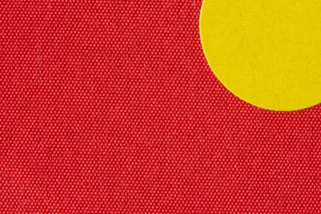 Macro image a yellow sticker on the texture of a red book coverの写真素材