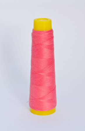 Pink yarn spool of thread on white background