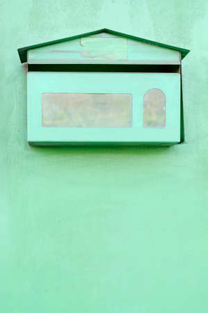 Green post box on green wallの写真素材