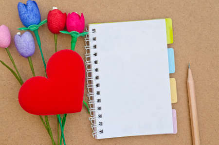 notebook with colorful artificial tulips flower made from silk cocoon, heart shape and pencil on wood backgroundの写真素材