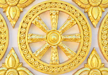 Thai style golden molding wheel of life pattern on temple wallの写真素材