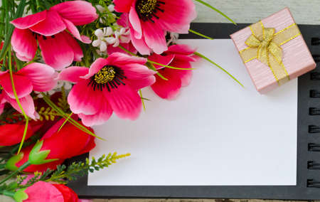 Bouquet of colorful flowers and gift box on open bookの写真素材