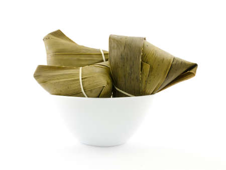 Traditional wrapped rice dumplings or zongzi in a bowl, isolated on white backgroundの写真素材