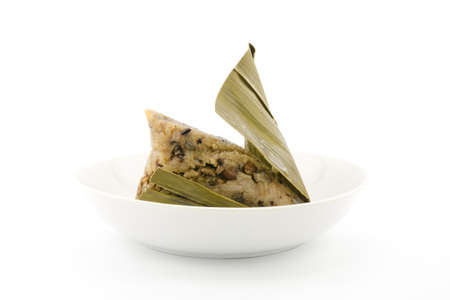 Traditional wrapped rice dumplings or zongzi on a plate, isolated on white backgroundの写真素材